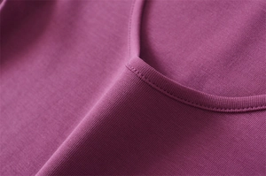 Close-up of purple knit fabric texture and stitching detail on the scoop neckline