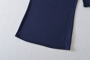 Detailed close-up of double-stitched hem on dark blue stretch knit slim fit top