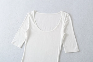 Close-up detail of smooth white fabric and U-neck stitching on the slim-fit top
