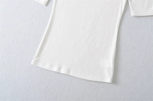 Detailed flat lay of white slim fit tee showing neat hem stitching and elastic fabric