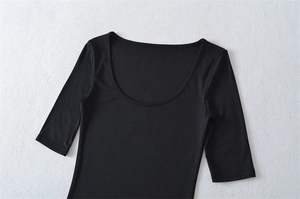 Close-up of black slim fit top with deep U-neckline and elastic knitted fabric detail