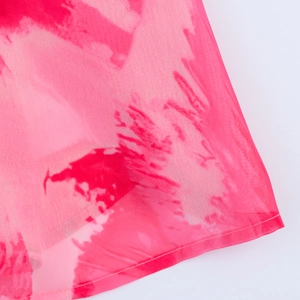 Détail macro d'une robe en mousseline rose montrant les coutures fines et la texture fluide