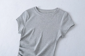 Detail view of grey short sleeve dress featuring elegant side ruching and pleated texture