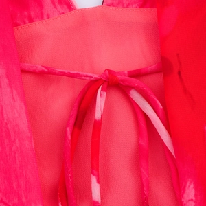 Vista detallada de un vestido de verano magenta con lazo estampado en el cuello y textura