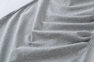 Detailed macro view of light grey knit fabric showing texture and soft pleat structure