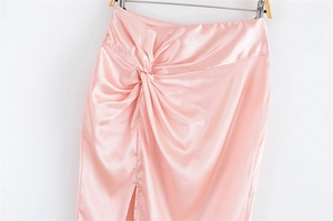 Detail eines rosa Satinrocks mit Knotendetail an der Taille und elegantem Gehschlitz