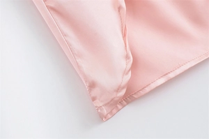 Nahaufnahme von rosa Satinstoff mit feiner Kantennaht und weicher Seidentextur