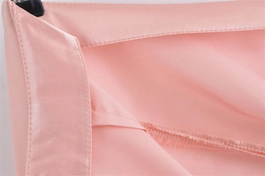 Detaillierte Nahaufnahme der glatten Satinstoff-Textur und der präzisen Nähte am rosa Rock