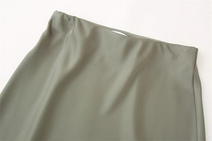 Dettaglio della vita di una gonna in raso verde oliva con trama setosa e design pulito