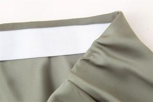 Dettaglio della fascia elastica bianca su gonna a trapezio in raso verde oliva lucido
