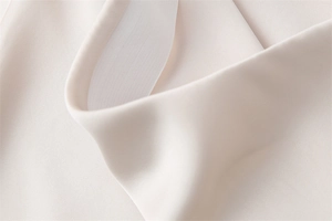 Dettaglio macro della gonna in raso di acetato beige con finitura liscia e cucitura interna