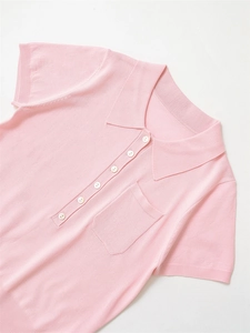 Détail d'un polo en maille rose montrant la texture fine et les boutons blancs contrastants