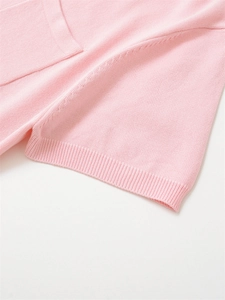 Détail de polo en maille rose montrant la texture fine et le bord-côte de la manche