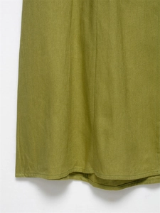 Close-up of grass green linen midi dress hem with detailed texture and stitching