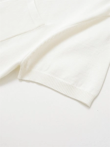 Gros plan sur la texture en maille fine et les bords-côtes du polo blanc épuré