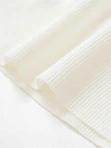Gros plan sur un tissu en maille côtelée blanche montrant une texture fine et un ourlet