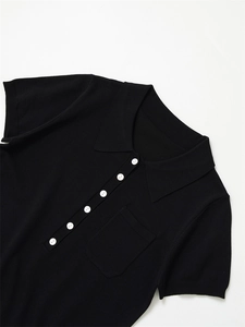 Détail d'un polo en maille noire avec boutons contrastés blancs et poche poitrine