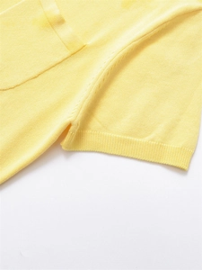 Gros plan d'un polo en maille jaune montrant la texture fine et les détails des bords-côtes