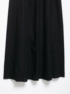Detailed macro view of black linen midi dress showing vertical seam and woven texture