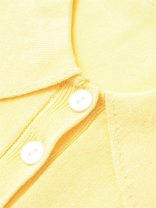 Gros plan détaillé sur un tricot jaune vif avec des boutons blancs sur un col polo