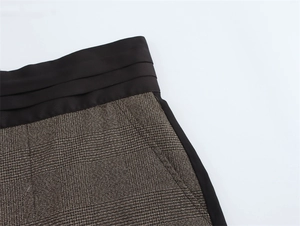 Dettaglio dei pantaloni a quadri a vita alta con patchwork nero e design a pieghe