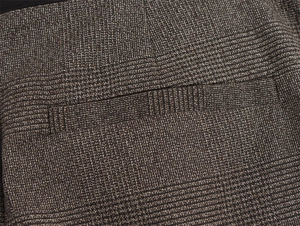 Dettaglio di pantaloni scozzesi a vita alta con tasca posteriore e trama del tessuto
