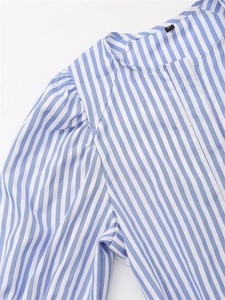Dettaglio dell'abito in popeline a righe blu e bianche con scollo a V e pieghe sulle spalle