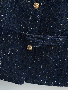 Detail der dunkelblauen Tweed-Weste mit goldenem Metallknopf und Glitzertextur
