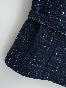 Detailaufnahme der dunkelblauen Tweed-Strickweste mit Goldpailletten und weißen Garnen