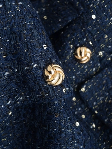 Details von dunkelblauem Tweed-Stoff mit Goldpailletten und strukturiertem Metallknopf