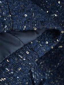 Makroaufnahme von blauem Tweed-Strick mit goldenen Pailletten und Satinfutter-Detail