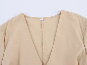 Detail van de V-hals op een abrikooskleurige geborduurde jurk met 1XL-maatlabel