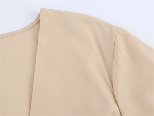 Detailopname van de hoogwaardige stiksels bij de halslijn van een beige geborduurde jurk