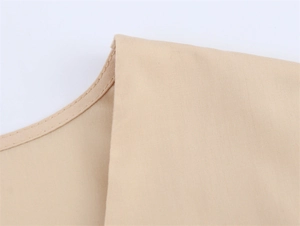 Macro-opname van V-hals stiksels op een beige geborduurde jurk met pofmouwen