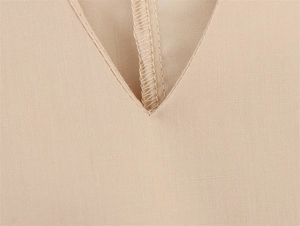 Detailopname van de V-hals stiksels en de beige geweven textuur van de stof