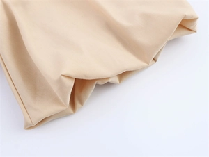 Detailopname van de beige katoenen borduurstof textuur op een jurk met pofmouwen