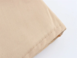 Macro-opname van nauwkeurige stiksels op de beige geborduurde jurk met V-hals en pofmouwen
