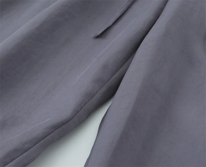 Detail der lilagrauen Paperbag-Hose mit Bindegürtel und gewebter Stofftextur
