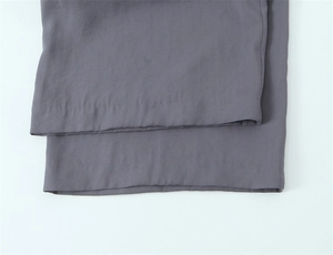 Detailaufnahme grauer Stoffhosen mit Fokus auf Materialtextur und präzise Saumnähte