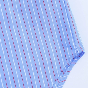 Detail view of light blue striped shirt featuring white and red lines and curved hem finish