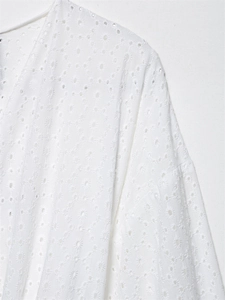 Vista macro dettagliata del tessuto in cotone bianco Broderie Anglaise con ricami floreali