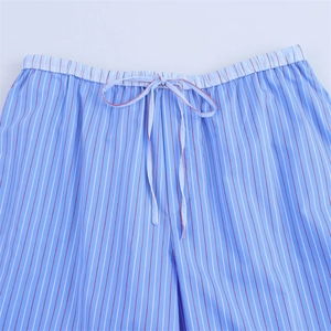 Detailed close-up of elastic waistband and drawstring on blue striped cotton trousers