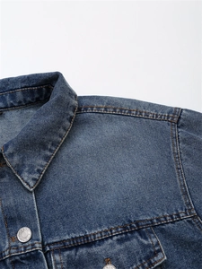 Detailansicht der Jeansjacke mit silbernen Knöpfen und kontrastreichen orangefarbenen Nähten