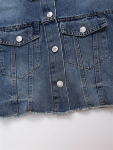 Detail einer dunkelblauen Jeansjacke mit Metallknöpfen und Fransensaum-Design