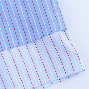 Close-up of high-quality striped cotton fabric with red and white lines on light blue