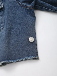 Detailaufnahme der Jeansjacke mit ausgefranstem Saum, Kontrastnähten und Metallknopf