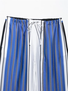 Détail d'un pantalon à rayures verticales avec taille élastique et cordon blanc à nouer