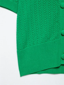 Detalle de blusa de punto verde con botones forrados a juego y puños de canalé elásticos
