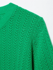 Detalle del top de punto verde esmeralda con textura de ganchillo calado y cuello acanalado