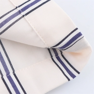 Vista dettagliata del tessuto twill bianco con strisce verticali e cuciture taglia-cuci